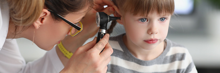家庭医生用特殊设备检查耳朵时 小女孩静静地坐着图片