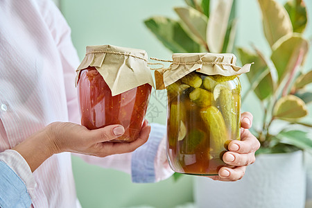 女性手中罐头中加咸黄瓜和西红柿高清图片