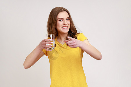 灰色背景的年轻情感女性的肖像手指玻璃矿物生活青少年黄色营养茶点饮食液体图片