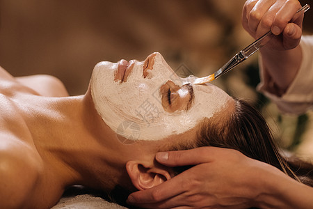 美容学家用面具遮住妇女的脸面 以恢复皮肤的活力美容院疗法沙龙程序服务病人护理黏土药品打扫图片