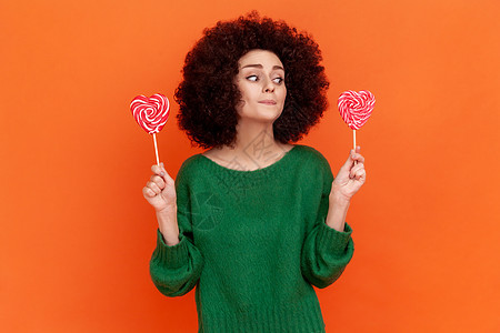在橙色背景下 画出有情感的年轻卷发女人的肖像糖果味道爆炸小吃甜点喜悦享受发型女孩圆圈图片