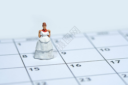 女性微型妇女站在日历之上 同时穿着婚纱 合身的一天概念和相片伴娘幸福衣服店铺精品购物女孩玩具配件房间图片