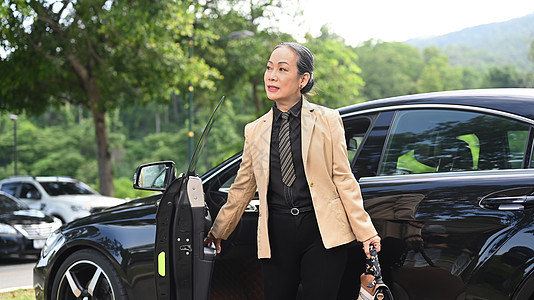 亚洲成熟的女商务人士 站在黑色车边停车站图片