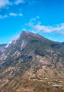 在一个小镇或村庄附近的山顶美丽的风景 夏日多云蓝天背景下的山峰宁静而优美的景色 郁郁葱葱的绿色植物和大自然的峰会图片