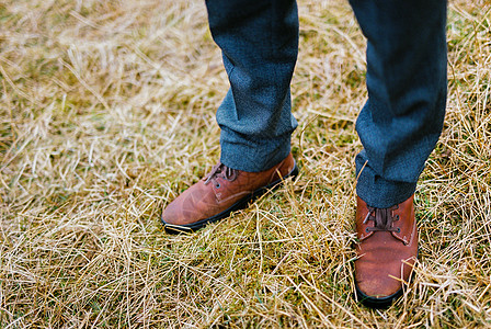 男人脚穿棕色鞋在干草上照片鞋类裤子靴子皮革成人鞋带叶子裁剪草地图片