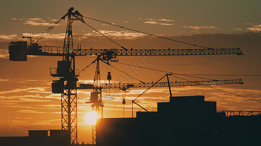 日落时市建筑起重机的轮椅太阳阳光工作工程财产工业黄色天空机器建筑学图片