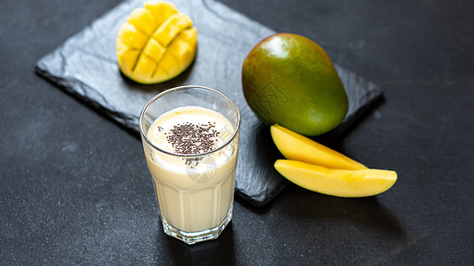 黑色背景上的凉爽芒果奶昔 夏天来一杯解渴 印度美食经典饮品——Lassi 牛奶 酸奶加芒果块图片