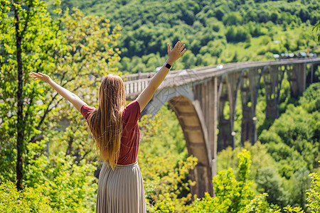 背景于特拉河沿岸的桥的妇女游客 在黑山周围旅行的概念旅游天空秀场峡谷石头地标公园男人基础设施塔拉图片