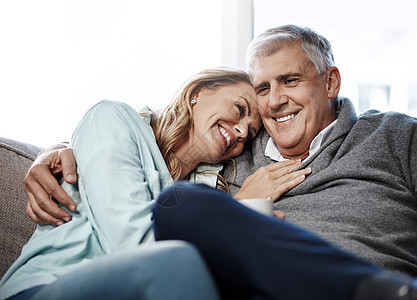 退休就是为了放松 一对成熟的夫妇在家里一起在沙发上放松休息室男人微笑长椅成人女士房子拥抱夫妻男性图片