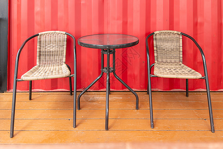 在路边咖啡厅红墙附近 空着的两张电线椅和玻璃桌高清图片