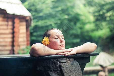 妇女户外享受热浴缸里的温泉洗澡游泳假期游客女孩治疗热水澡黑发水池热带图片