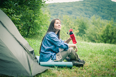 妇女在帐篷附近的山上 是可喜的女士森林活动远足旅游女性岩石享受游客成人图片