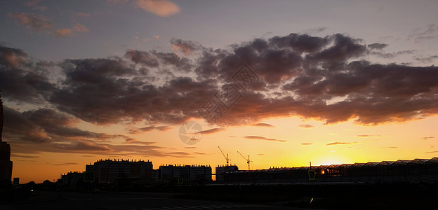 在夕阳和建筑物轮廓的背景下 傍晚橙色天空中的云彩图片