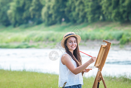 户外美丽的女孩艺术家女性成人画架画笔绘画帆布头发天赋闲暇褶皱图片