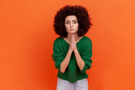 穿着绿色休闲风格毛衣的爆炸式发型的恳求女人保持双臂祈祷姿势并请求宽恕 为错误感到抱歉图片