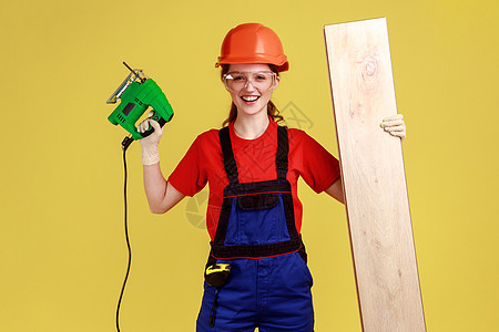 年轻快乐的正木匠女性 工作与壁锯 持有木板图片
