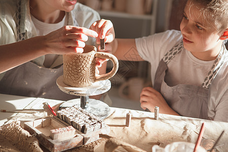 母亲和生子制造波特陶瓷艺术家男生学习艺术孩子闲暇老师娱乐儿子图片