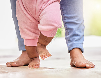 混血父母和小女儿的脚在家里一起站在地板上的低特写 妈妈在教她的小宝宝走路 学习迈出第一步的孩子图片