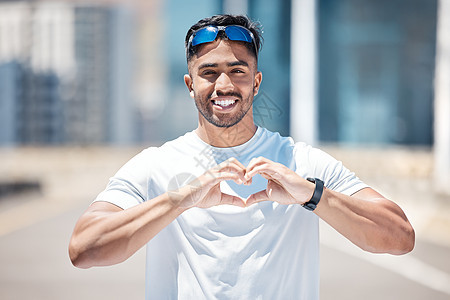 快乐的年轻男运动员站在城市道路上用手做心形 适合运动员进行户外跑步 因为有氧运动有益于心脏健康背景图片
