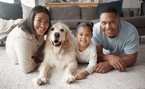 一个幸福的混血家庭三口之家的画像 他们带着狗在休息室的地板上放松 充满爱心的黑人家庭对寄养动物深情款待 年轻夫妇与女儿亲密无间 图片