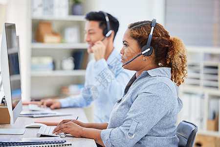 专注的年轻混血女性呼叫中心电话营销代理在办公室的电脑上工作时戴着耳机交谈 严肃的非裔美国女商务人士顾问运营服务台以提供客户服务支图片