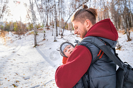 婴儿在冬天的森林中走过 他怀着孩子的父亲的怀抱图片