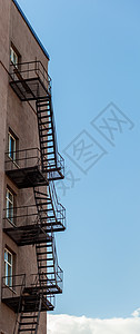 蓝天对面高楼大楼的火灾逃生梯的休全月房子楼梯摄影建筑学阳台火灾砖墙商业城市梯子图片