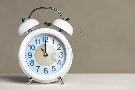 十一点闹钟 一个白色的闹钟在一张白色的桌子上 时钟指针指向 11 点 时间更改为夏令时或冬令时 设置 11 00 或 23 00图片