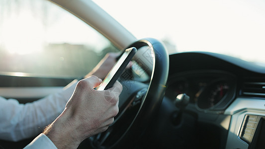 坐在车里用手机打在线信息的面目全非的人的特写手 在汽车中使用电话的商务人士特写视图 事故保险 聊天司机图片
