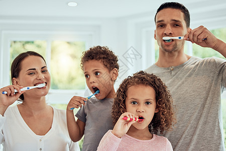 快乐的混血父母和他们的两个孩子在家里一起刷牙 年轻夫妇教他们的孩子养成良好的卫生习惯 四口之家 小女孩和男孩一起准备爸爸女孩家庭图片