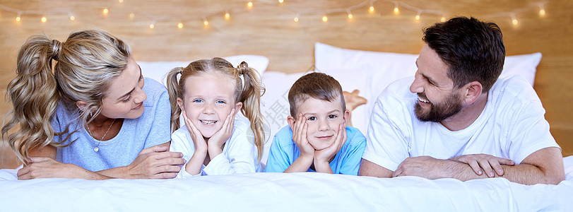 快乐无忧无虑的白人家庭躺在床上舒适地躺在家里 同时在家里在一起 慈爱的父母与小儿子和女儿共度美好时光 可爱的孩子们和爸爸妈妈一起图片