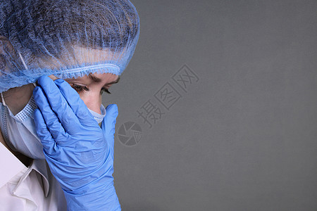 身戴医帽 面罩和手套的女医生擦眼泪从她脸上抹去图片
