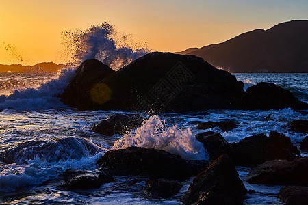 海浪在西海岸日落时撞向岩石图片