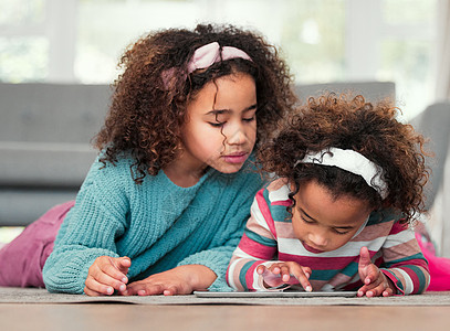 两个小女孩在家里一起玩数字平板电脑游戏 和两个女孩共度难关图片