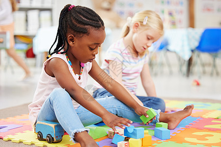 在学前班或幼儿园的地板上玩五颜六色的教育玩具积木的非洲裔美国小女孩和同学 孩子们在进行创造性学习和发展的同时获得乐趣图片