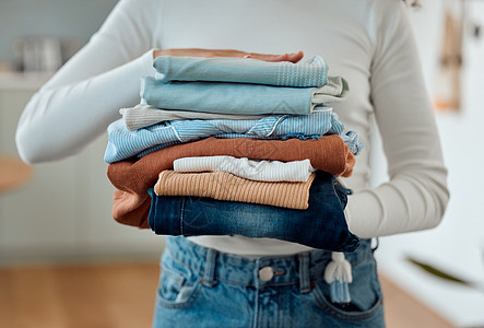一个女人手里拿着一堆要洗的衣服 女人拿着一叠整齐折叠的衣物 女人在家里清洗衣服 家里拿着一堆新鲜 干净的衣服的女人图片