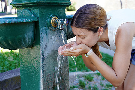 水合物紧急缺水 年轻女性在城市热量暴涨时从喷泉里取水水背景