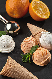 近距离拍摄的奶油和橙色冰淇淋 在黑暗的黑本底锥体石头香草产品食物涂鸦甜点托盘味道服务图片