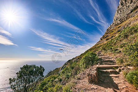 一条远足径爬上一座落基山 绿色植物生长 蓝天多云背景 大自然中靠近海洋的美丽沿海徒步地点的小径景观图片