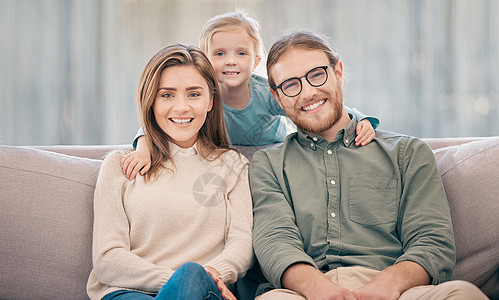 财富站在那些把家庭放在首位的人身边 一个快乐的年轻男人和女人和他们的女儿在家里的沙发上放松的画像图片