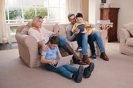 欢迎使用新的绑定方式 一个年轻的家庭在家里一起使用他们的电子设备时建立联系图片