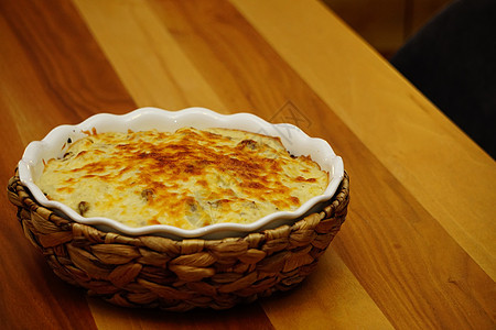花椰菜 配有贝沙梅酱和在陶瓷盘中用草垫覆盖的顶部熔化奶酪图片