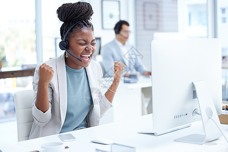 一个年轻的呼叫中心探员在办公室的电脑上工作时 正在欢呼着呢 这太疯狂了 她只是控制不住自己的兴奋感图片