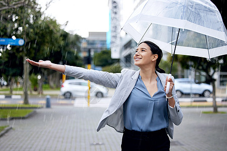 一位年轻的女商务人士在走去上班时享受雨的滋味 不怕被淋湿图片