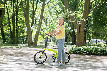 在公园里休息的退休妇女 灰头发的波斯女人在夏日带着自行车散步成人妻子运动微笑骑术老年假期活动训练女性图片