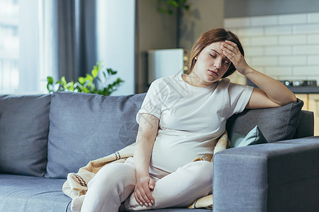 怀孕妇女生病 头痛 手放在头后 她的头部有问题母性症状女性疼痛挫折失败父母沙发腹部长椅图片