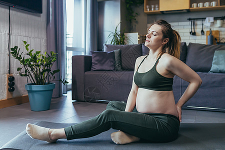 孕妇瑜伽孕妇在锻炼后感到身体疼痛 背靠着腿坐在家里等她躺着背景
