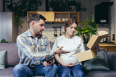 一个年轻的家庭 一个孕妇和一个男人不小心收到了别人的包裹消费者运输震惊盒子衣服顾客纸板船运父母纸盒图片