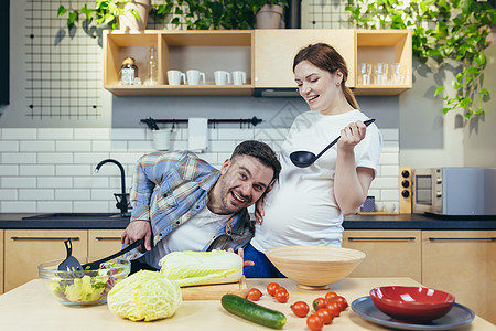 一个年轻的家庭 一名孕妇和一名男子一起准备健康美味的食物沙拉服务摄影父亲父母亲热帮助享受微笑厨房图片