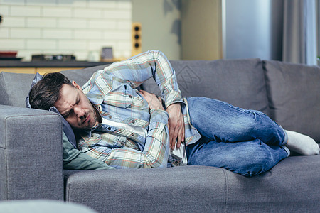 躺在家里沙发上的病人腹部痛得要命症状成人男性胰腺休闲装酒精食物胀气卫生药品图片